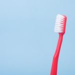 ¿Qué cepillo de dientes es más adecuado para mi? por Morales Cervera. Cepillo de dientes rosa sobre fondo azul.