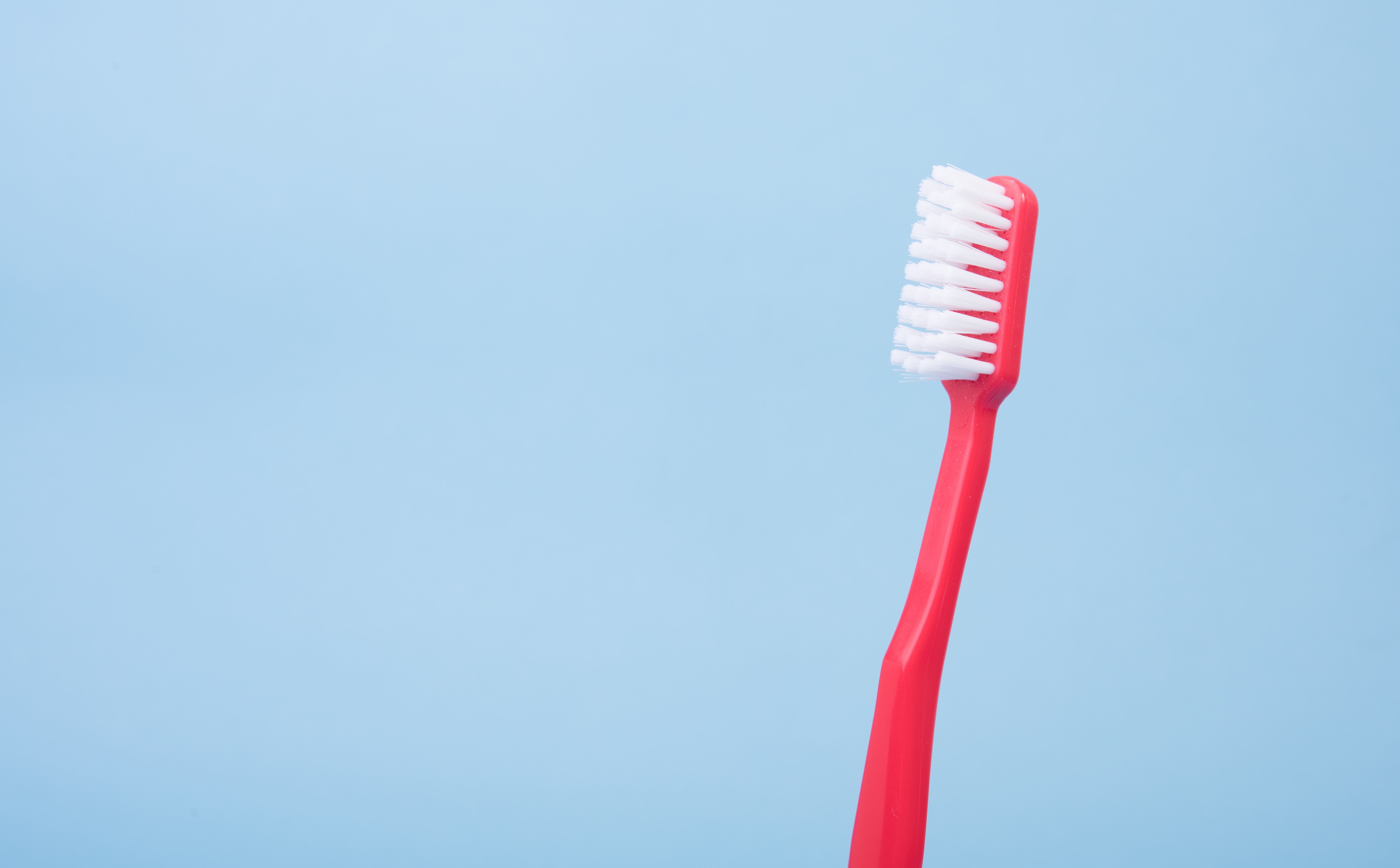 ¿Qué cepillo de dientes es más adecuado para mi? por Morales Cervera. Cepillo de dientes rosa sobre fondo azul.