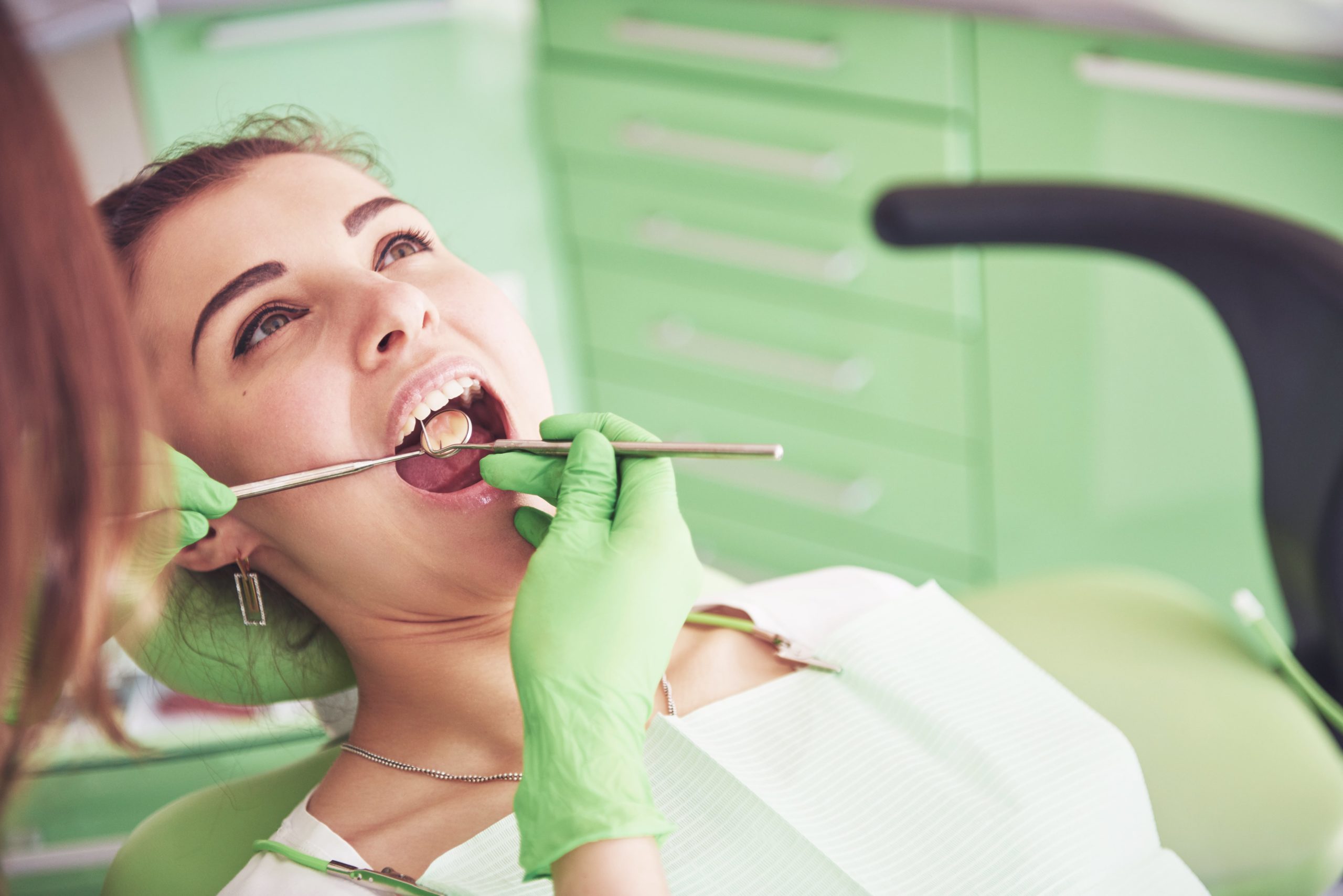 Chica tumbada en un sillón de gabinete dental, posiblemente realizándose una evaluación dental. Podría ser con dentistas en Palencia, para verificar si tiene papiloma oral.