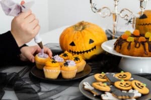 Decoración de cupcakes y galletas temáticas de Halloween con calabazas, junto a dulces y postres, destacando la importancia de cuidar los dientes durante las fiestas