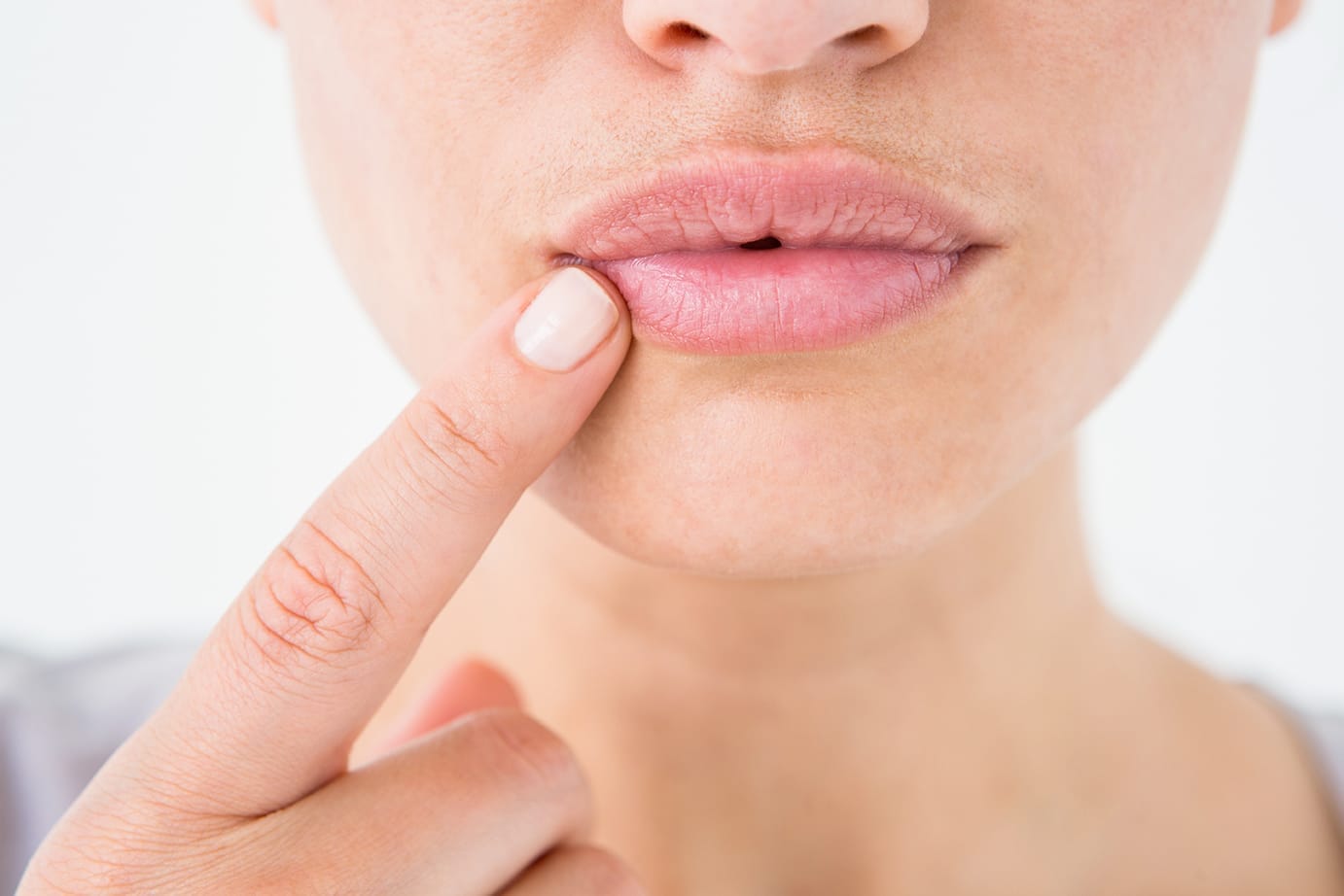 Primer plano de una persona tocándose la comisura de los labios, señalando una zona afectada por boqueras.